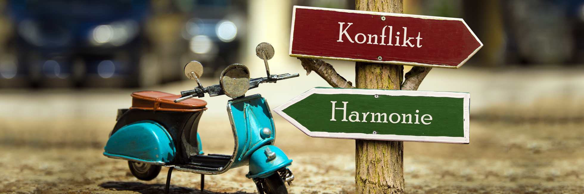 Bild mit einem Vesparoller an einem Richtungsweiser mit der Wahl Konflikt oder Harmonie