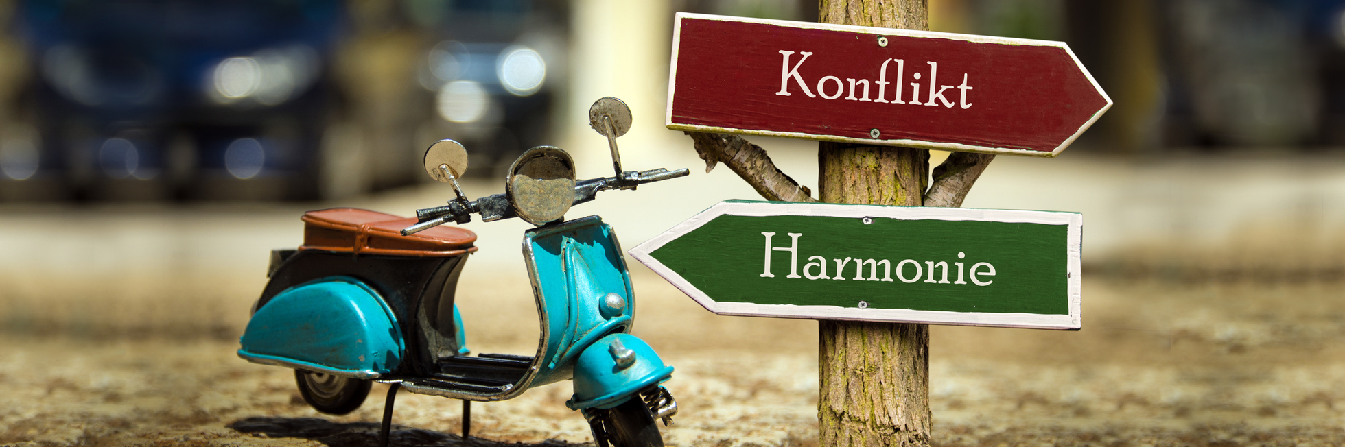 Bild mit einem Vesparoller an einem Richtungsweiser mit der Wahl Konflikt oder Harmonie